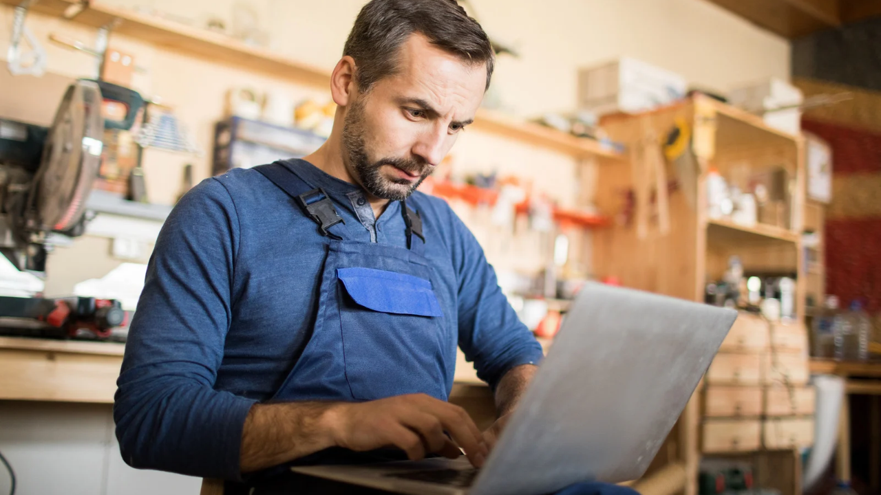 small business owner in workshop reviewing HR on laptop